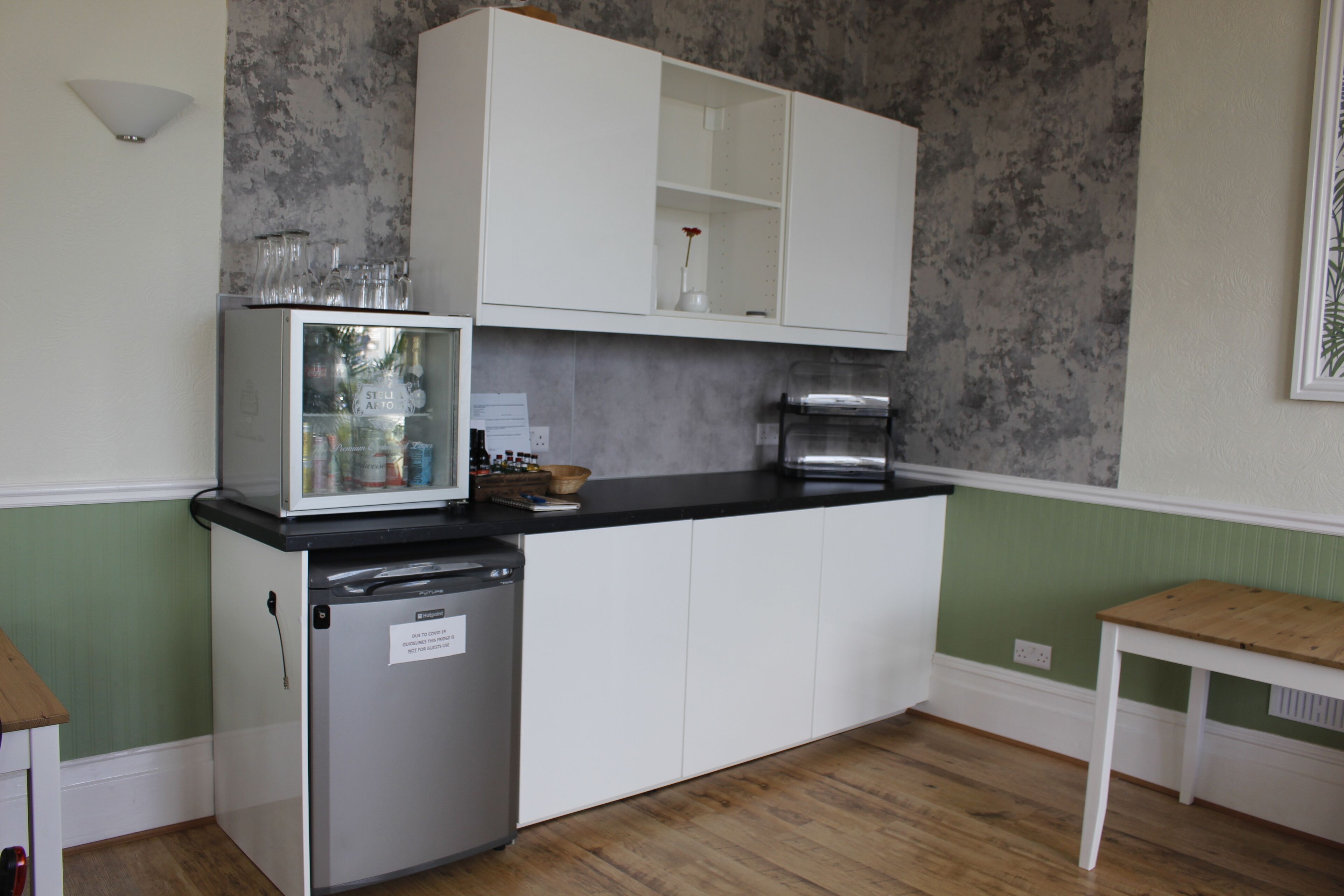 A compact kitchen with a refrigerator, a sink, and a countertop with a coffee maker.