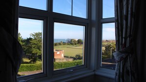 Una habitación con un ventanal grande que ofrece vistas a un paisaje verde y un edificio lejano.