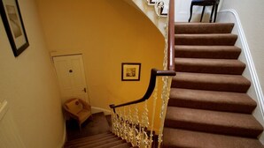 Una escalera alfombrada con barandilla de madera y una puerta blanca al final.