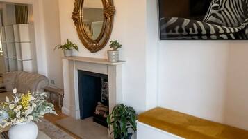 A living room with a fireplace, a bench, a sofa, a coffee table, and a painting of a zebra.