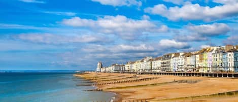 A coastal town with a long promenade, colorful buildings, and a clear sky.