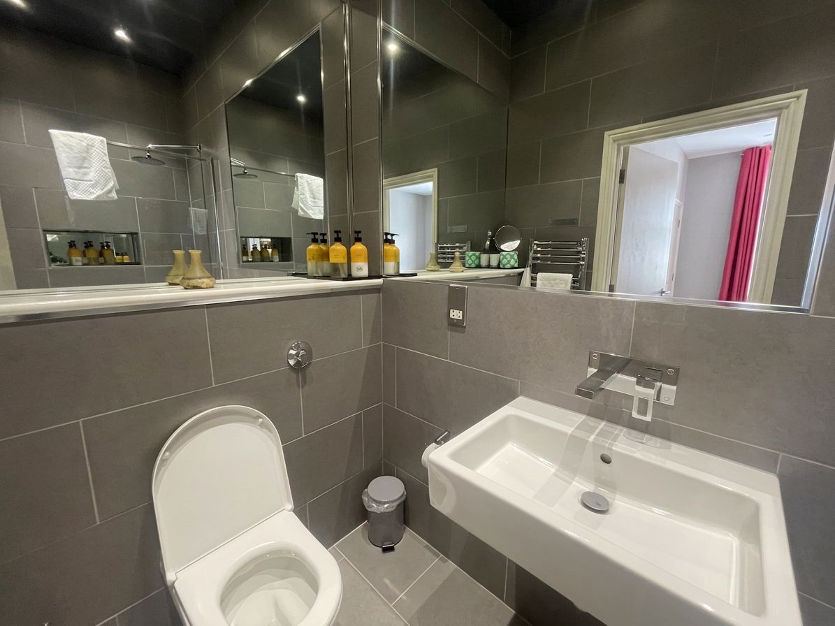 A modern bathroom with a toilet, sink, and large mirror.