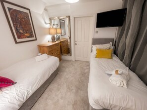 A hotel room with two beds, a TV, a mirror, a dresser, and a door.