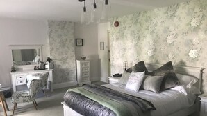 A bedroom with a large bed, a dresser, a vanity with a mirror, and a desk. - The Great House Hotel & Restaurant (Bridgend)