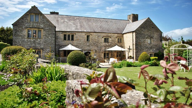 A stone building with a large lawn and outdoor seating area. - The Great House Hotel & Restaurant (Bridgend)