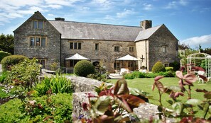 A stone building with a large lawn and outdoor seating area. - The Great House Hotel & Restaurant (Bridgend)
