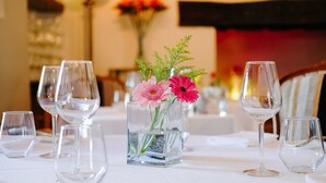A table set with wine glasses and a vase with flowers. - The Great House Hotel & Restaurant (Bridgend)