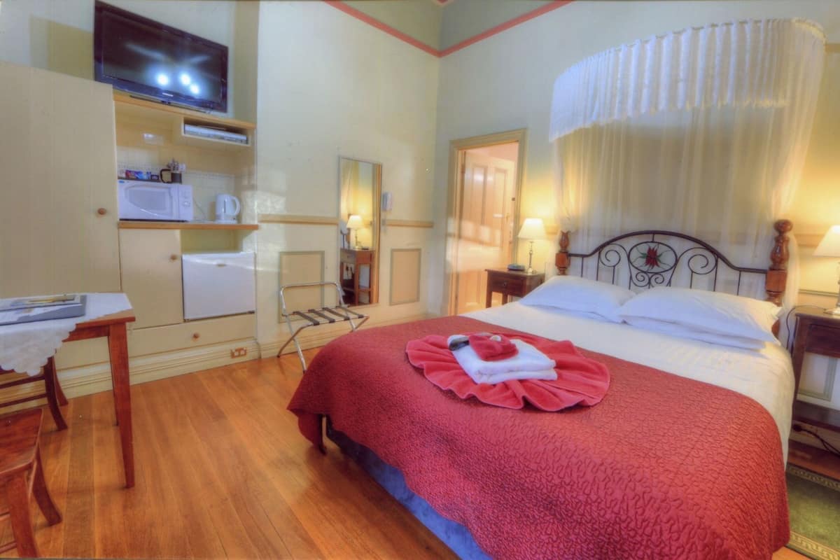 A hotel room with a bed, a desk, a television, and a wardrobe.