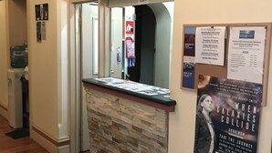 En reception med en stenskrivebord, en opslagstavle med eventplakater og en vandkøler.