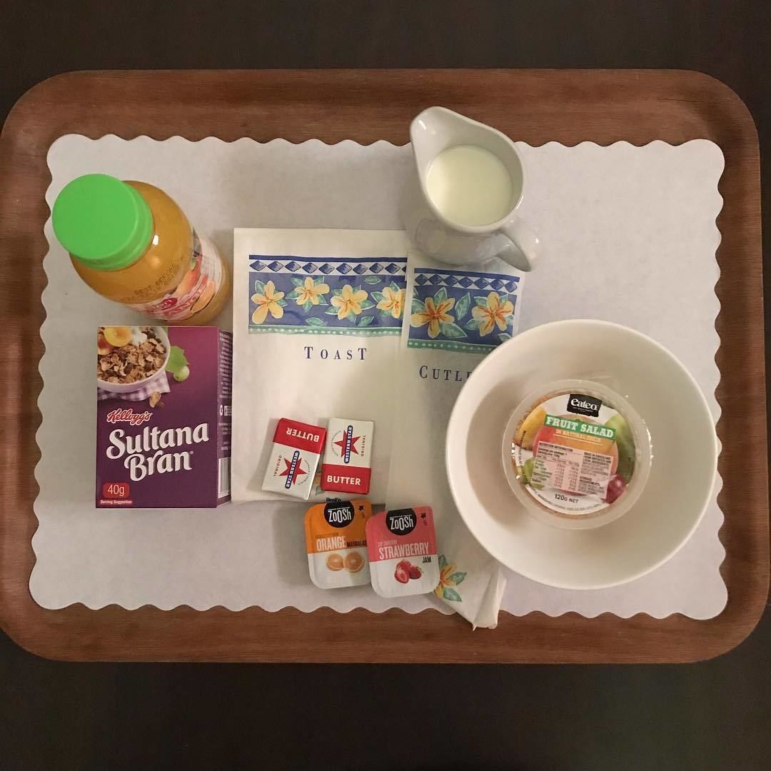 A tray with food items including toast, butter, fruit salad, and cereal.