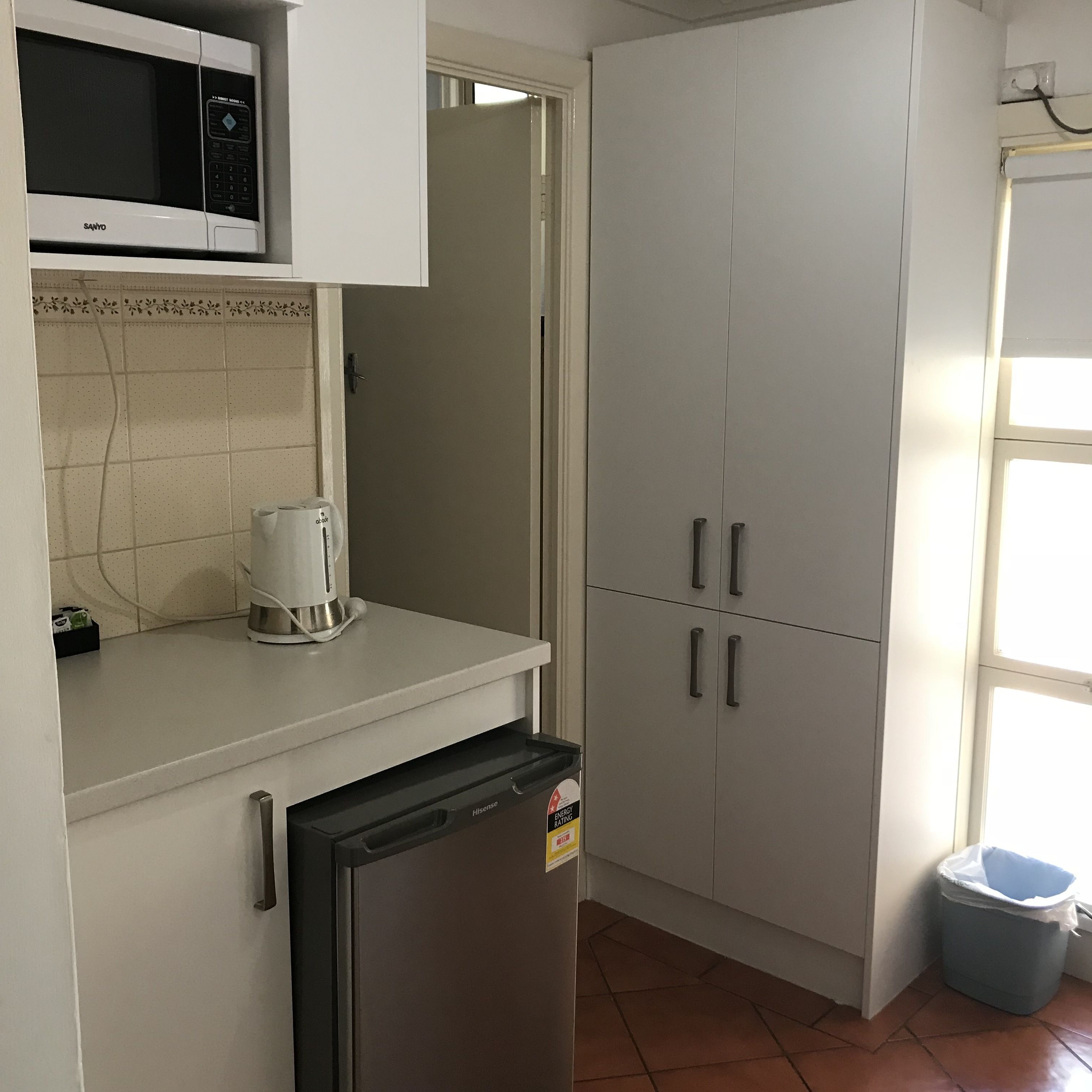 A kitchen with a microwave, coffee maker, refrigerator, and cabinets.