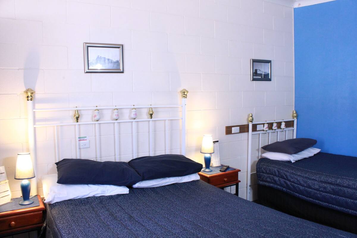 A hotel room with two beds, white walls, and a blue accent wall.