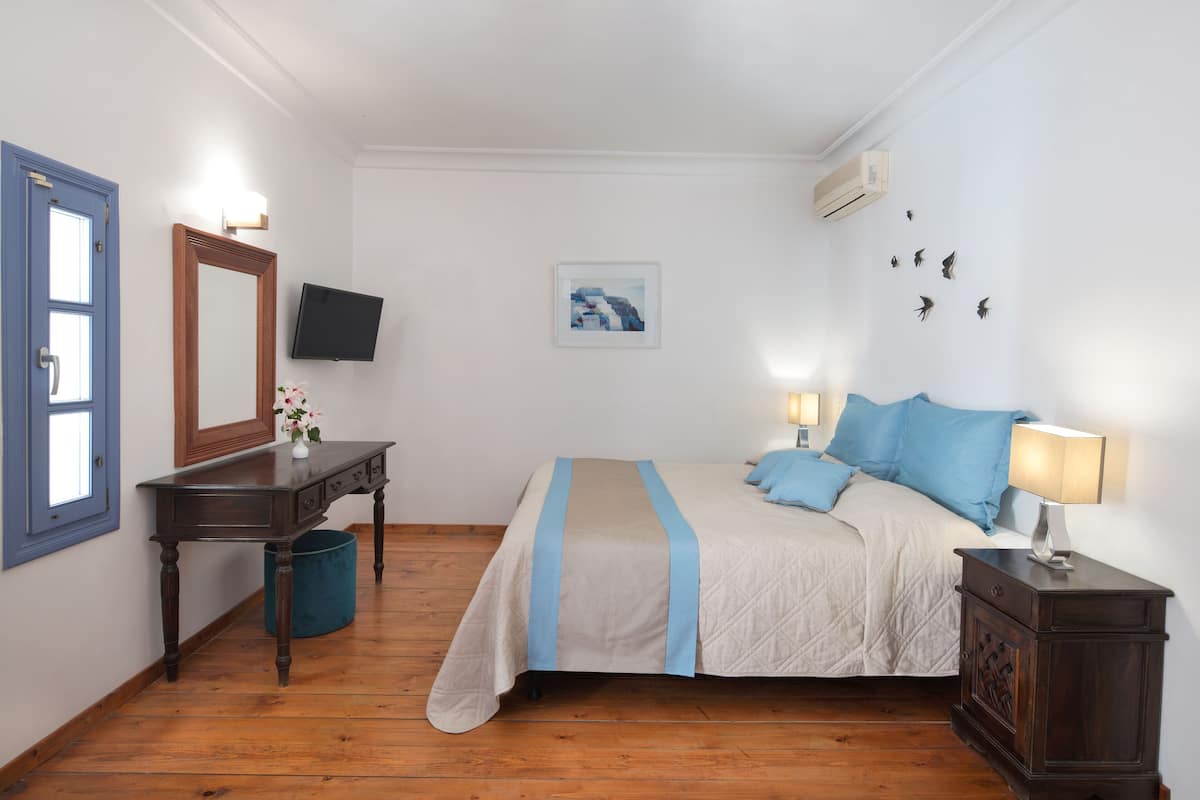 Une chambre à coucher avec un lit, une table de chevet, une commode et un téléviseur fixé au mur.