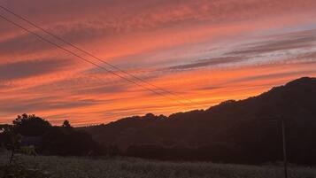 A sunset over a hilly landscape with power lines.