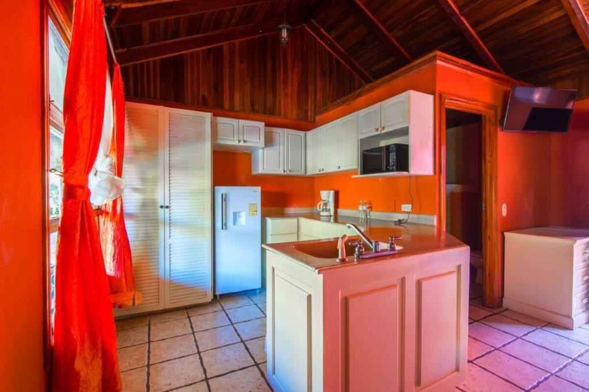 A compact kitchen with white cabinets, a central island with a sink, and a microwave.