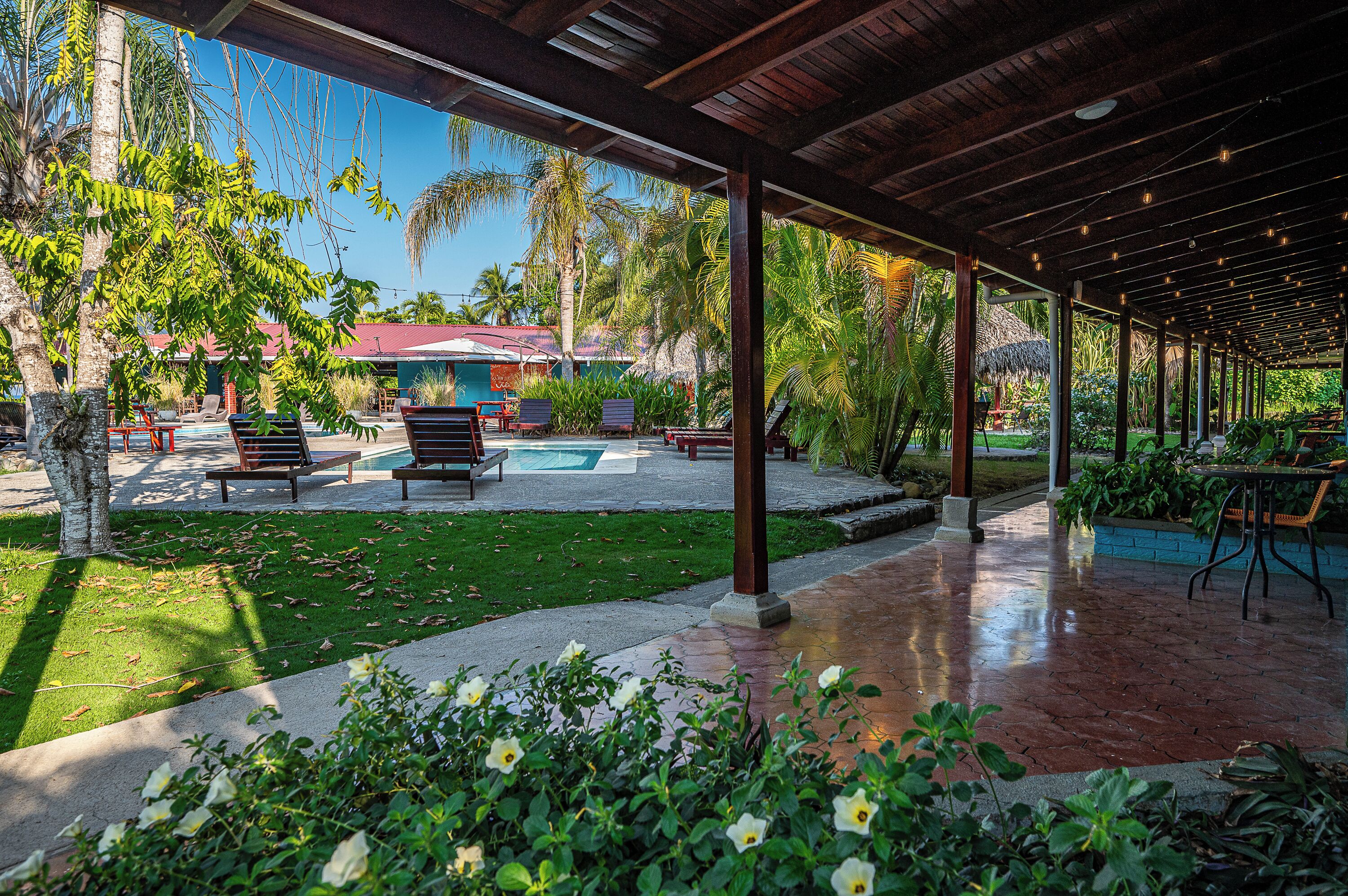 A covered outdoor area with a pool, seating, and lush greenery.