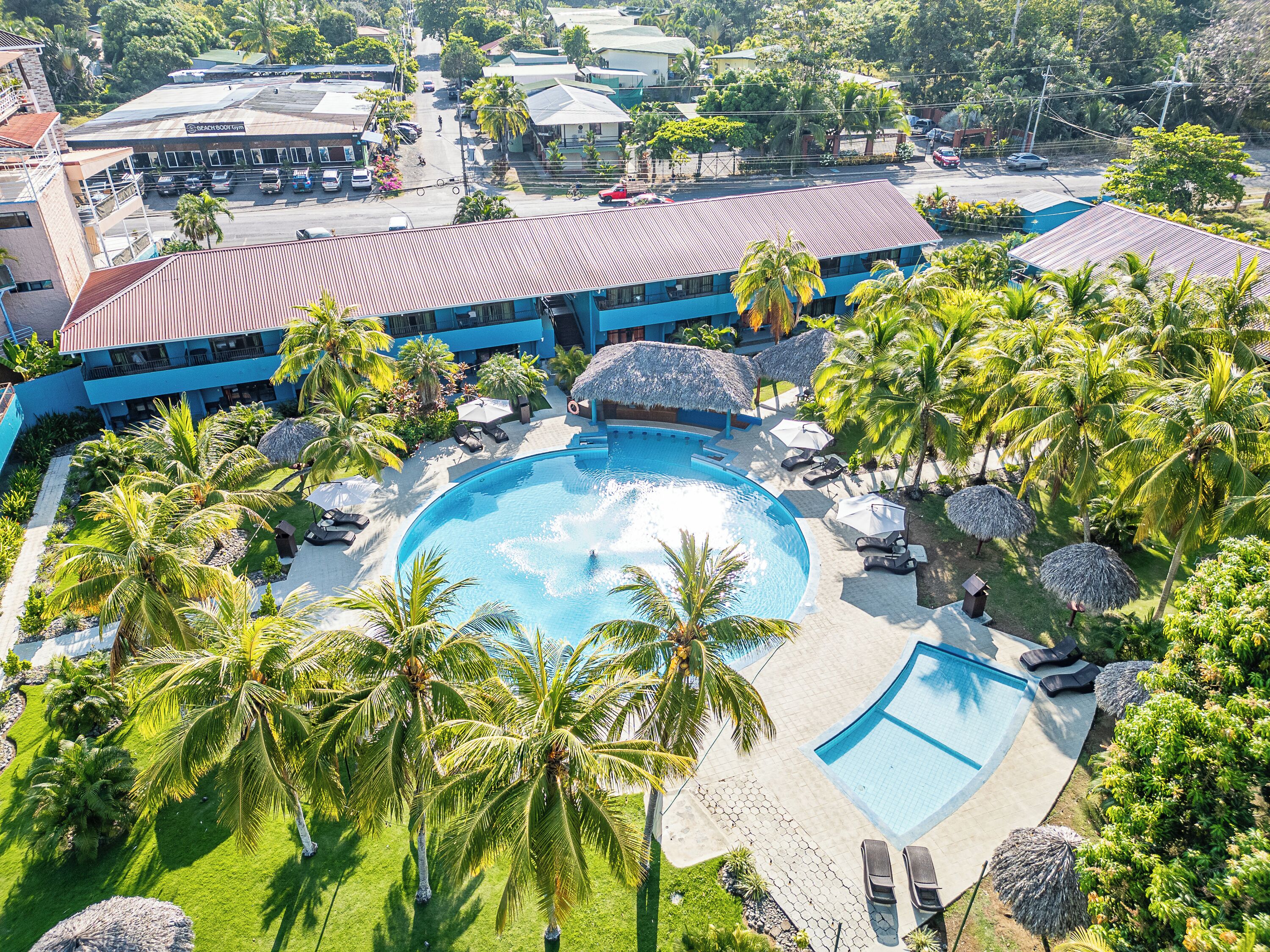 Een resort met een groot zwembad, omringd door palmbomen en ligbedden.