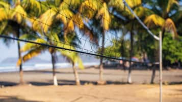 En la playa, camastros, toallas de playa y vóleibol de playa