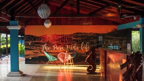 A reception area with a wooden ceiling, a mural, and a reception desk. - Beach Break Resort (Jacó)