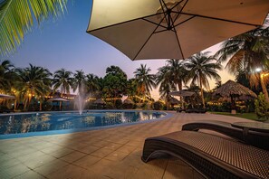 A pool area with lounge chairs, palm trees, and a fountain.