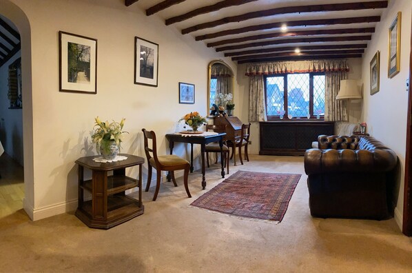 A cozy living room with a dining area, featuring a piano, a leather sofa, and a dining table with chairs.