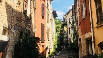 A narrow street flanked by historic buildings with stone walls and wooden shutters.