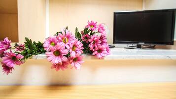 A wooden table with a bouquet of pink flowers in a vase.