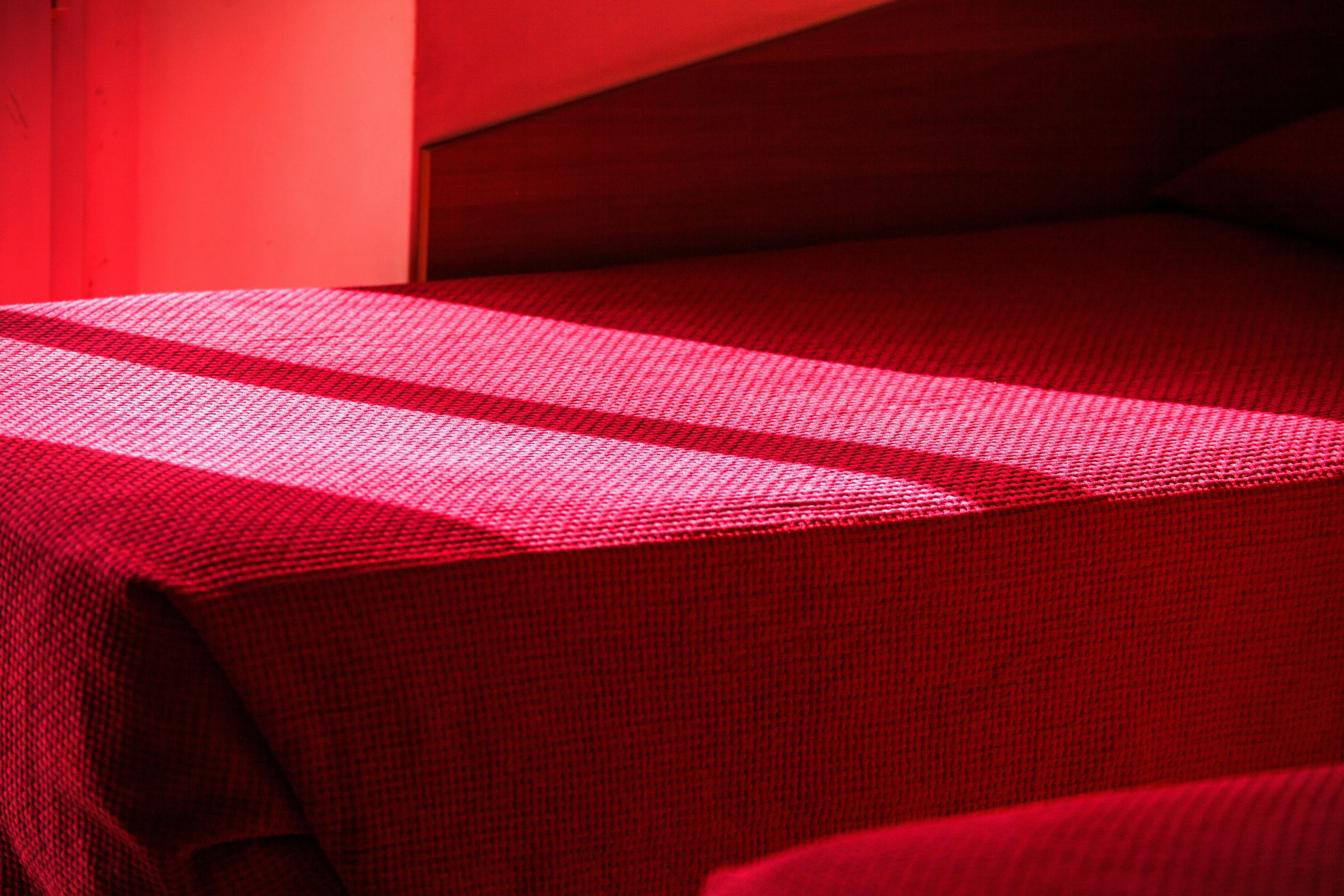 Un lit avec une couvre-lit rouge et une tête de lit en bois.