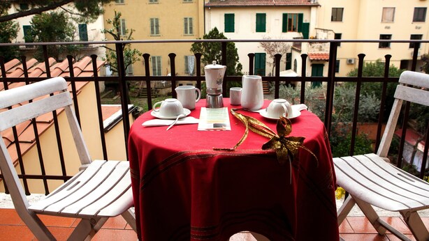 A balcony with a red tablecloth, white chairs, and a coffee setup. - Hotel Villa Il Castagno (Florence)