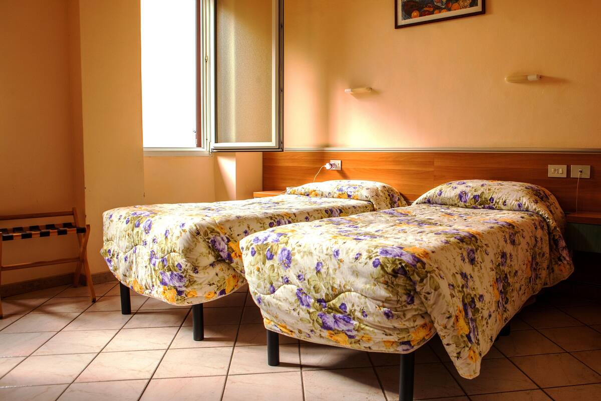 Une chambre avec deux lits, une fenêtre et un tableau au mur.