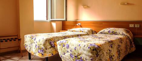 A room with two beds, a window, and a painting on the wall.