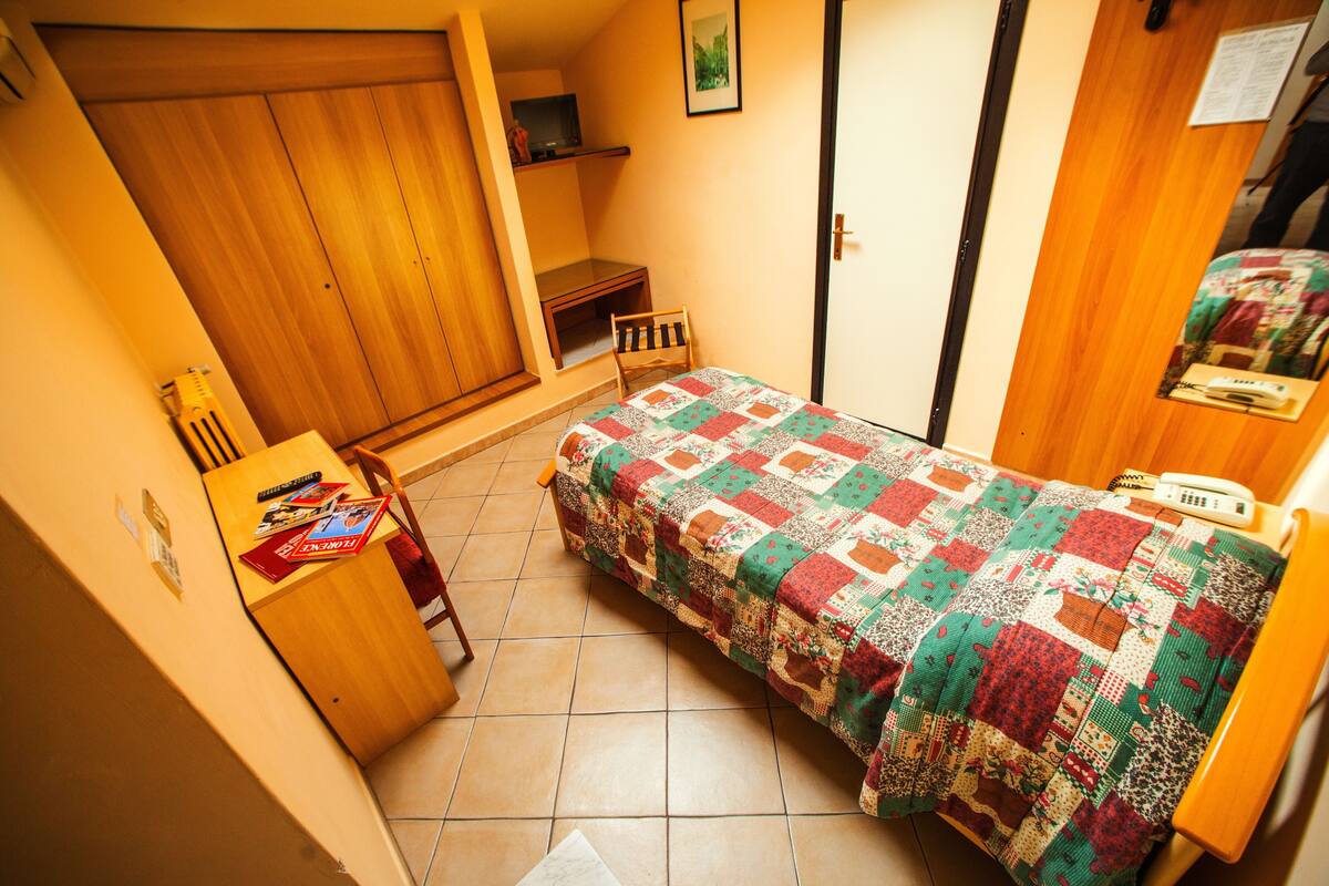 Une petite chambre à coucher avec un lit, un bureau et une armoire.