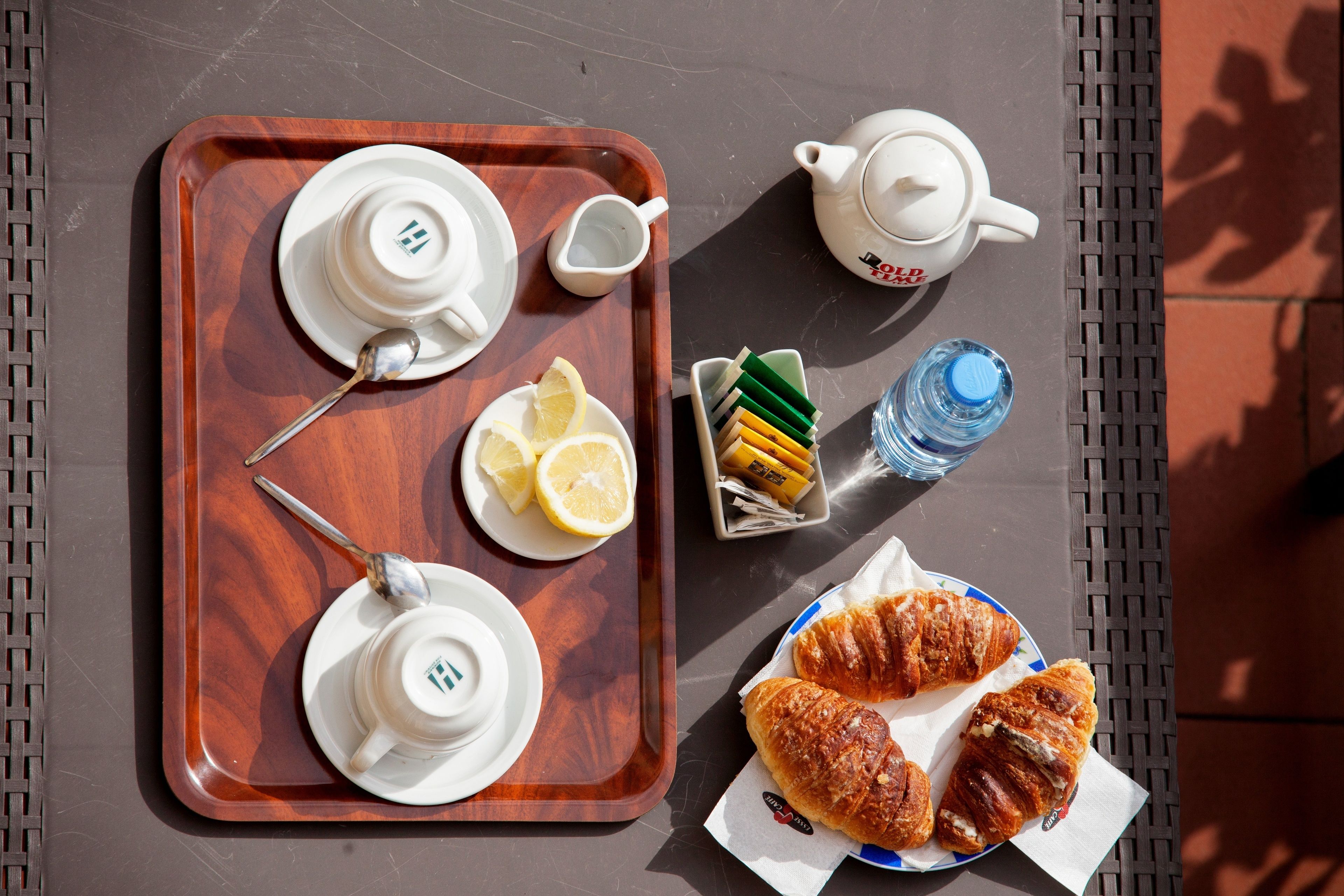A tray with teapots, cups, lemon slices, and a water bottle on a table.