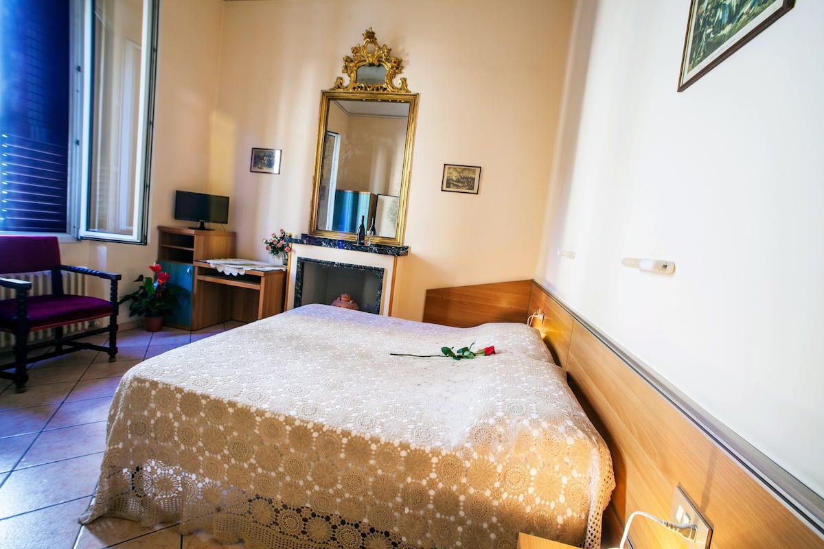 Une chambre bien rangée, avec un lit, un bureau, une chaise, un miroir et une fenêtre.