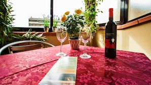 A table with a red floral tablecloth, two wine glasses, a bottle of wine, a menu, and a potted plant with yellow flowers. - Hotel Villa Il Castagno (Florence)