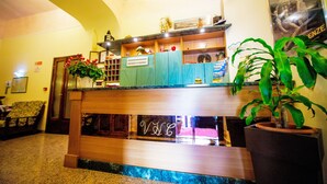 A reception area with a wooden counter, a neon sign, and a potted plant. - Hotel Villa Il Castagno (Florence)