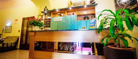 Una zona de recepción con mostrador de madera, un letrero de neón y una planta en maceta.