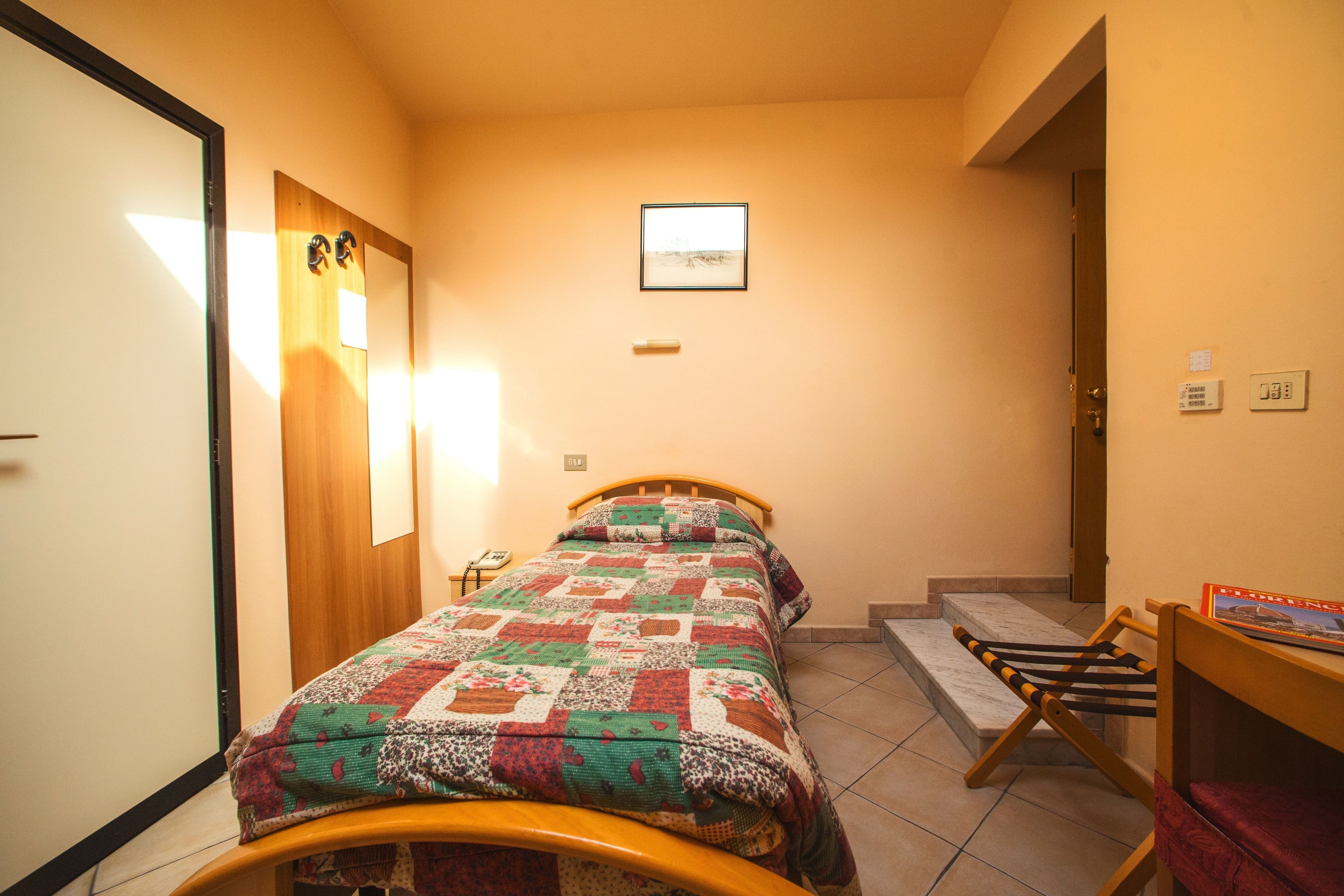 Un dormitorio pequeño y acogedor con una cama, un escritorio de madera y una pequeña mesa con una silla.