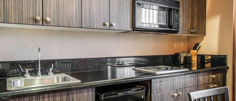 A kitchen with a built-in microwave, stainless steel sink, and dishwasher.