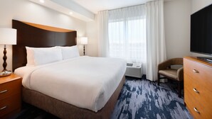 A hotel room with a large bed, a desk with a lamp, a chair, a TV, and a window with curtains. - Fairfield Inn & Suites by Marriott Fort Pierce (Fort Pierce)