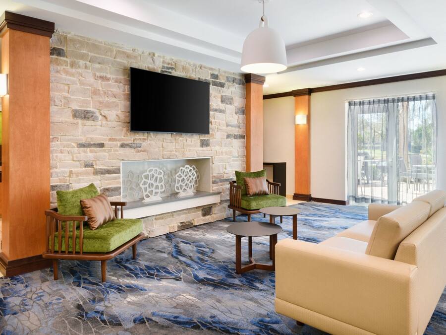 A modern living room with a stone wall, a flat-screen TV, a fireplace, and comfortable seating.