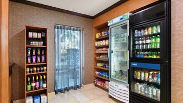 Una camera d'albergo con un minibar, un frigorifero fornito di bevande e un ripiano con degli snack.