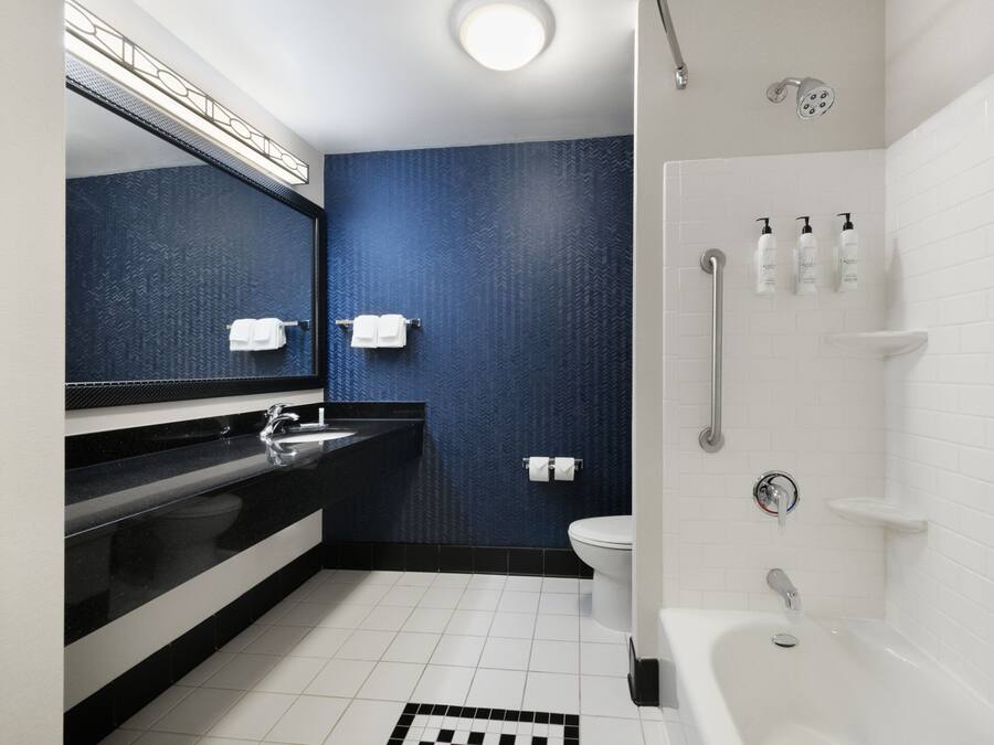 A modern bathroom with a black countertop sink, a white toilet, and a white bathtub.