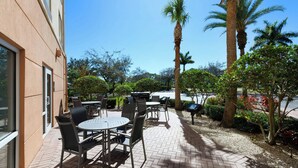 An outdoor patio with tables and chairs, surrounded by palm trees and other greenery. - Fairfield Inn & Suites by Marriott Fort Pierce (Fort Pierce)