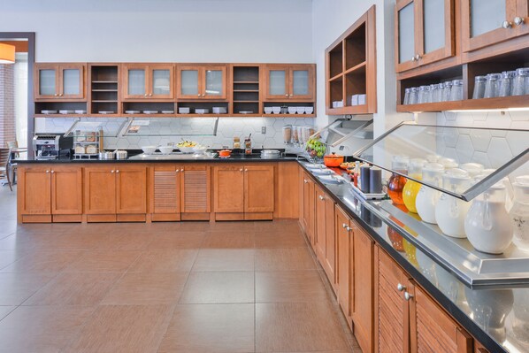 A modern kitchen with wooden cabinets, a stainless steel countertop, and a glass display case.