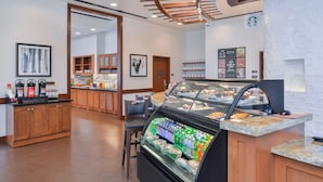 Mostrador de una panadería con pasteles y un dispensador de bebidas.