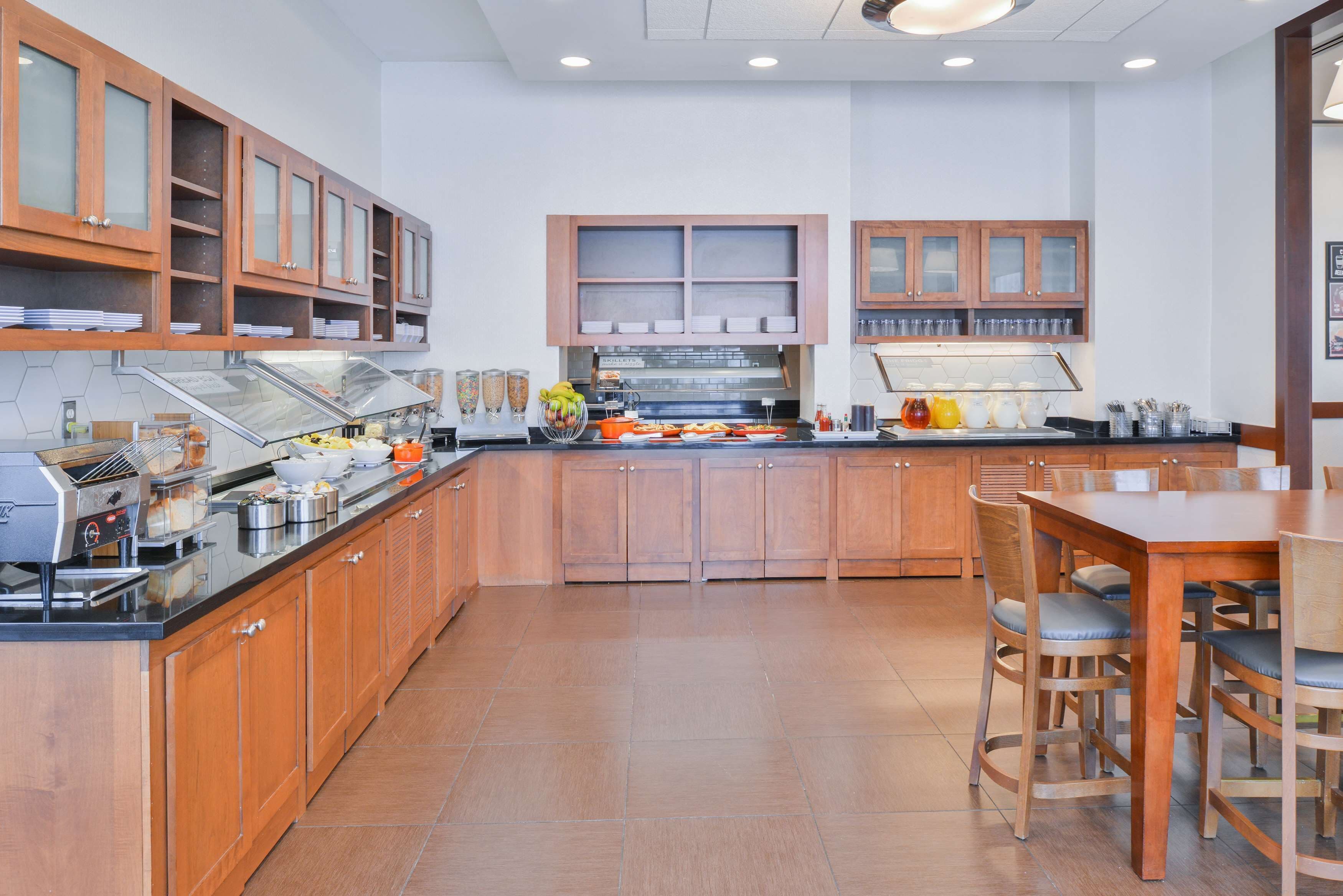 Una cocina moderna con armarios de madera, una isla central y un comedor con sillas.