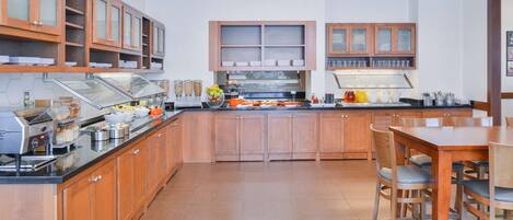A modern kitchen with wooden cabinets, a central island, and a dining area with chairs.