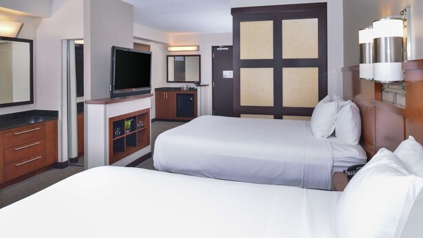 Habitación de hotel con dos camas, televisión, minibar y baño.