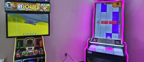 Two arcade machines, one for Big Buck Hunter and another for Piano Keys, with a purple wall in the background.